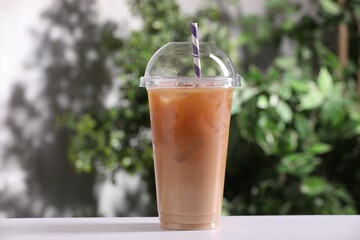 Tasty iced coffee on white table against blurred background