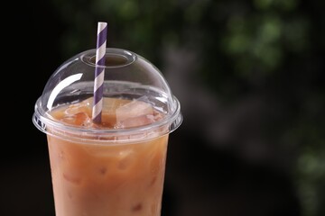 Tasty iced coffee against blurred background, closeup. Space for text