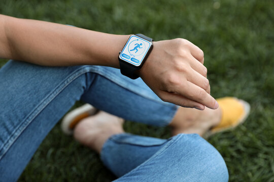 Woman checking smart watch with step counting app outdoors, closeup