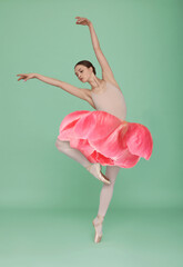 Young ballerina dancing on light green background. Peony flower instead of woman's skirt