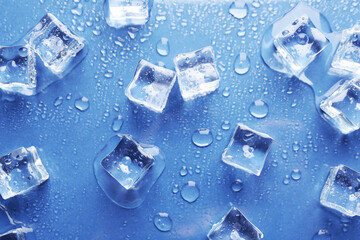 Melting ice cubes and water drops on blue background, flat lay
