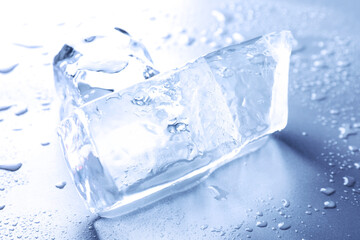 Pieces of clear ice and water drops on light blue table