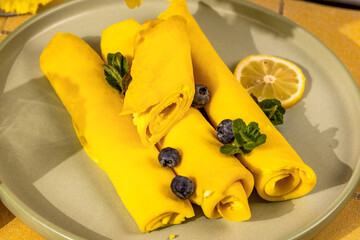 Delicious golden pancakes with lemon and blueberries drizzled with honey