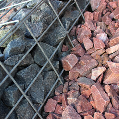 Colored crushed stones in the mesh fence and scattered around it. Modern landscaping environmental facility development