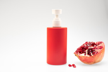 Red Cosmetic Pump Bottle with Pomegranate on White Background