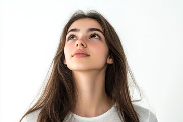 Fototapeta premium Cheerful Young Brunette Woman Gazing Upwards Against a Bright White Backdrop in Studio Setting