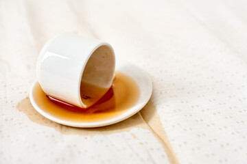 Spilled coffee on white fabric with saucer