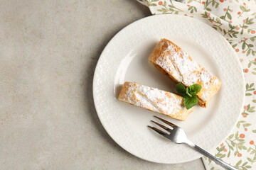 Pieces of tasty apple strudel with powdered sugar and mint on grey textured table, top view. Space for text