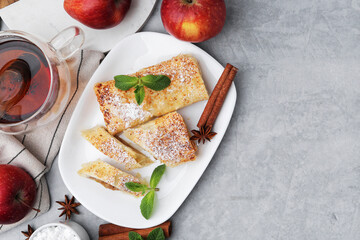 Tasty apple strudels served on light grey table, flat lay. Space for text