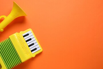 Toy accordion and horn on orange background, flat lay. Space for text