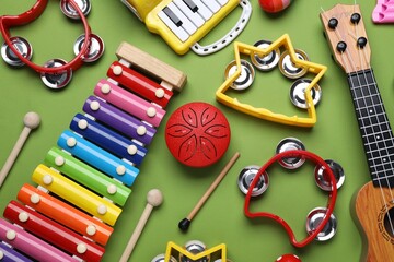 Different toy musical instruments on green background, flat lay