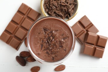Tasty chocolate milk with shavings and pieces on white table, flat lay