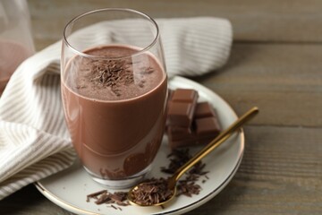 Tasty chocolate milk with shavings and pieces on wooden table, closeup