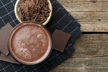 Tasty chocolate milk with shavings and pieces on wooden table, flat lay. Space for text