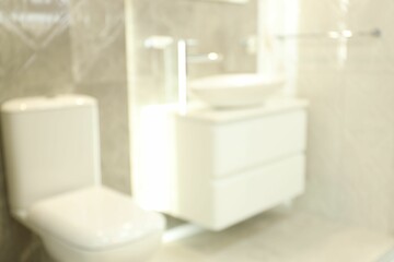 Blurred view of stylish bathroom with vanity and toilet bowl near tiled wall. Interior design