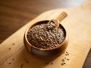 flax seeds in a rustic wooden bowl on a wooden table with copy space
