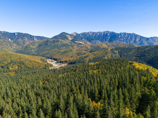 Scenic panorama of peaceful countryside in Romania with green hills, mountains, and autumn forest.