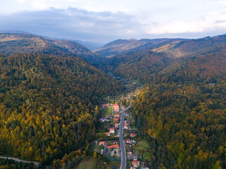 Scenic panorama of peaceful countryside in Romania with green hills, mountains, and autumn forest.