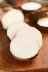 Freshly cut slices of cassava, manioc  or yuca (lat. Manihot esculenta) on wooden board (Selective Focus, Focus through the middle of the first slice)