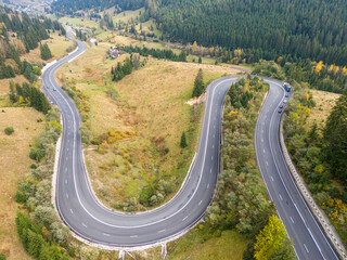 vibrant autumn colors of a forest with a winding asphalt road, aerial view