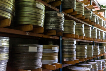 Vintage film reels stored on wooden shelves in a dark room