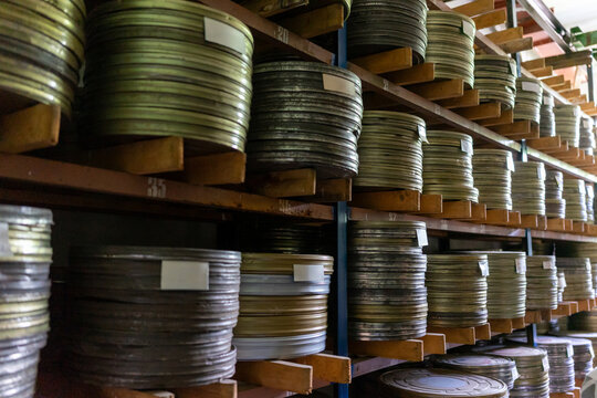 Vintage film reels stored on wooden shelves in a dark room