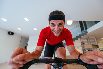 A triathlete riding a triathlon bike on a machine simulation in a modern living room. Training...