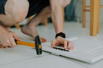 A young guy is repairing a retro lock on a locker door.