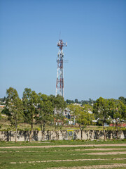 Obraz premium Cell phone tower with antennas contrasting the technology with the foliage of the trees at its base