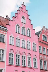 Fototapeta premium Historic pink building with ornate windows stands in a vibrant neighborhood under a clear blue sky showcasing architectural beauty and charm in a lively urban landscape