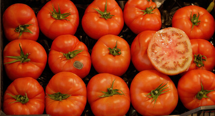 Fresh ripe red tomatoes with half a tomato showing inside at a market stall
