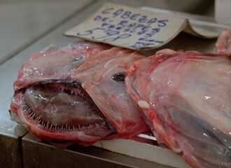 Monkfish heads showing sharp teeth lying on fish market stall