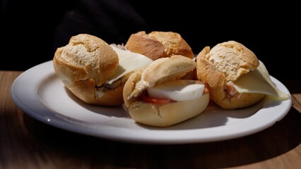 Spanish tapas - Delicious mini sandwiches resting on white plate on wooden table