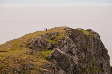 A couple standing on a rocky hill overlooking the ocean