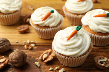 Delicious carrot cupcakes and walnuts on wooden table, closeup