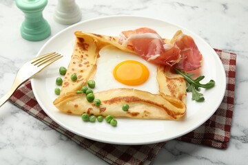 Delicious crepe with egg, bacon, arugula and green peas on white marble table, closeup