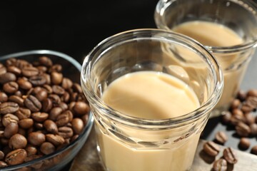 Coffee cream liqueur in glasses and beans on table, closeup