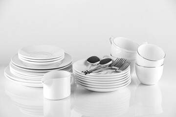 Different clean dishware and cutlery on light background