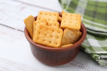 Tasty salty crackers on white wooden table, closeup