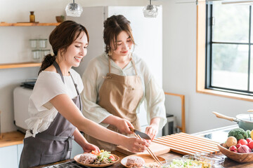 料理教室・クッキングスクールで料理を教える講師の女性と生徒の女性
