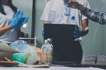Close-up of female hands from a family collecting plastic waste and bottles from the ground. They...