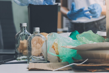 Close-up of female hands from a family collecting plastic waste and bottles from the ground. They...