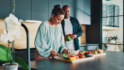 Mature couple, help and cooking in kitchen with vegetables, knife and support with meal prep in home. People, man and woman with ingredients, cutting board and together for food, diet or nutrition