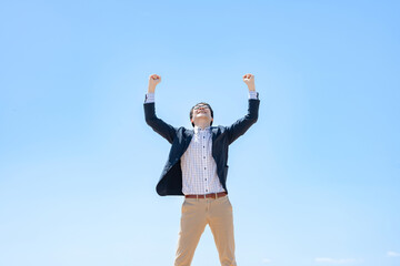 青空の下でガッツポーズをする男性