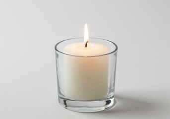 Close up of a white candle burning in a clear glass holder on a white background surface view