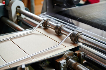 Fototapeta premium Detailed view of a machine folding cardboard box flaps in an industrial setting