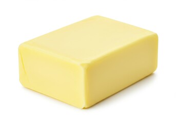 A single block of yellow butter sitting on a white surface in a studio setting with soft lighting