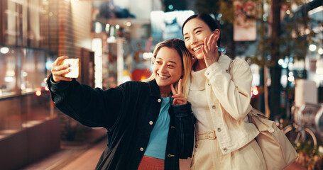 Happy, asian women and night with peace sign for selfie, photography or picture in Toky city. Japan, female people or friends with smile or emoji for travel, memory or capture moment in an urban town