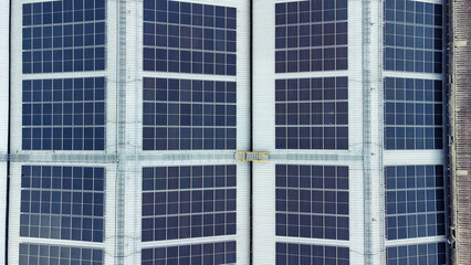 Obraz premium multiple solar panels installed on the rooftop of a building. The solar panels are arranged in neat rows and columns, with clear separations between each panel. 