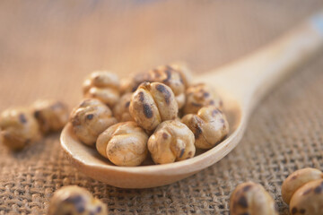 Roasted chickpeas on a wooden spoon against a burlap background